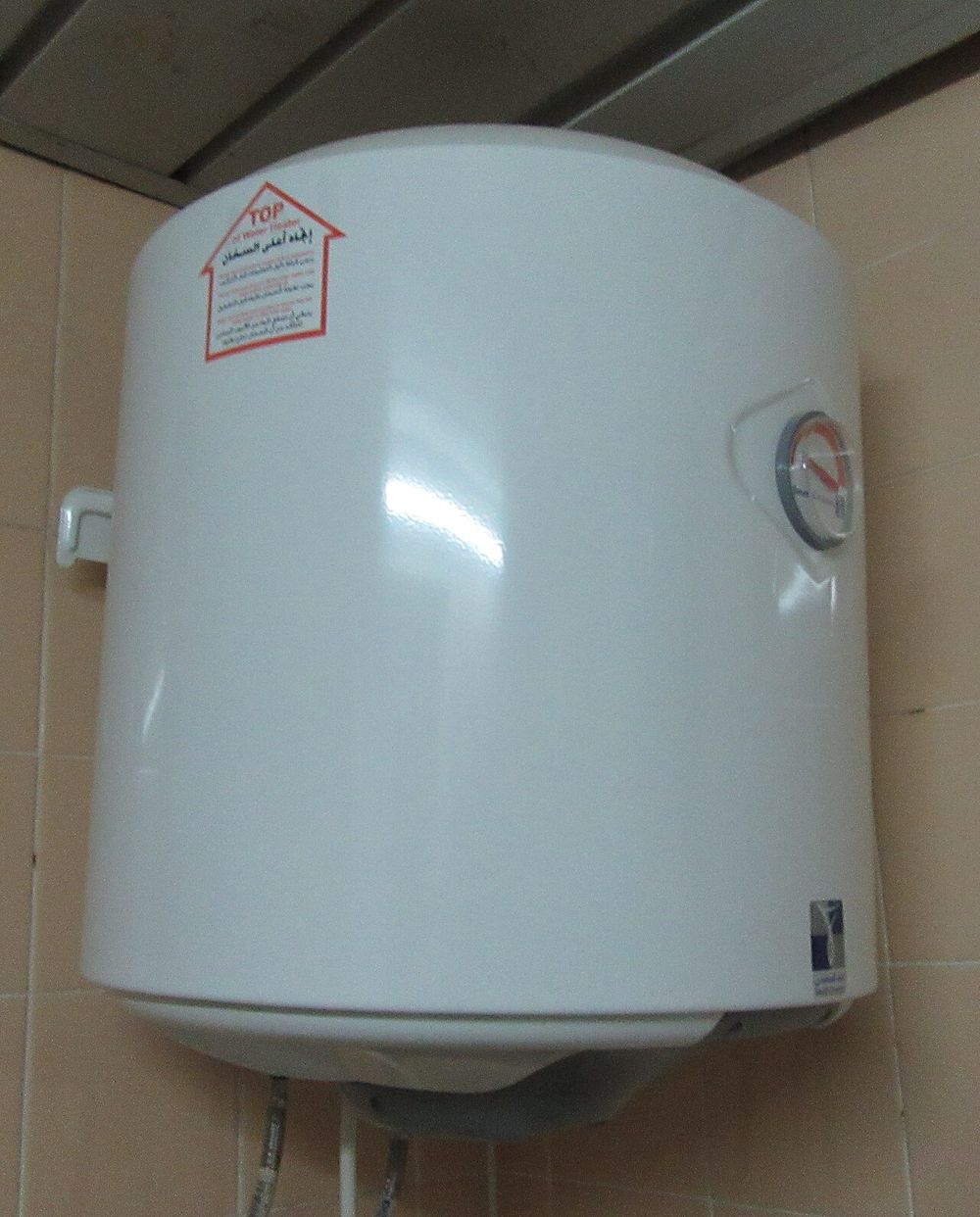 A white tank water heater mounted on a tiled wall