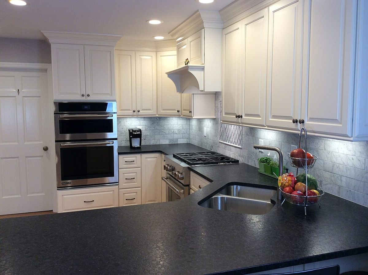 A bright kitchen with white cabinets and a black stone counter
