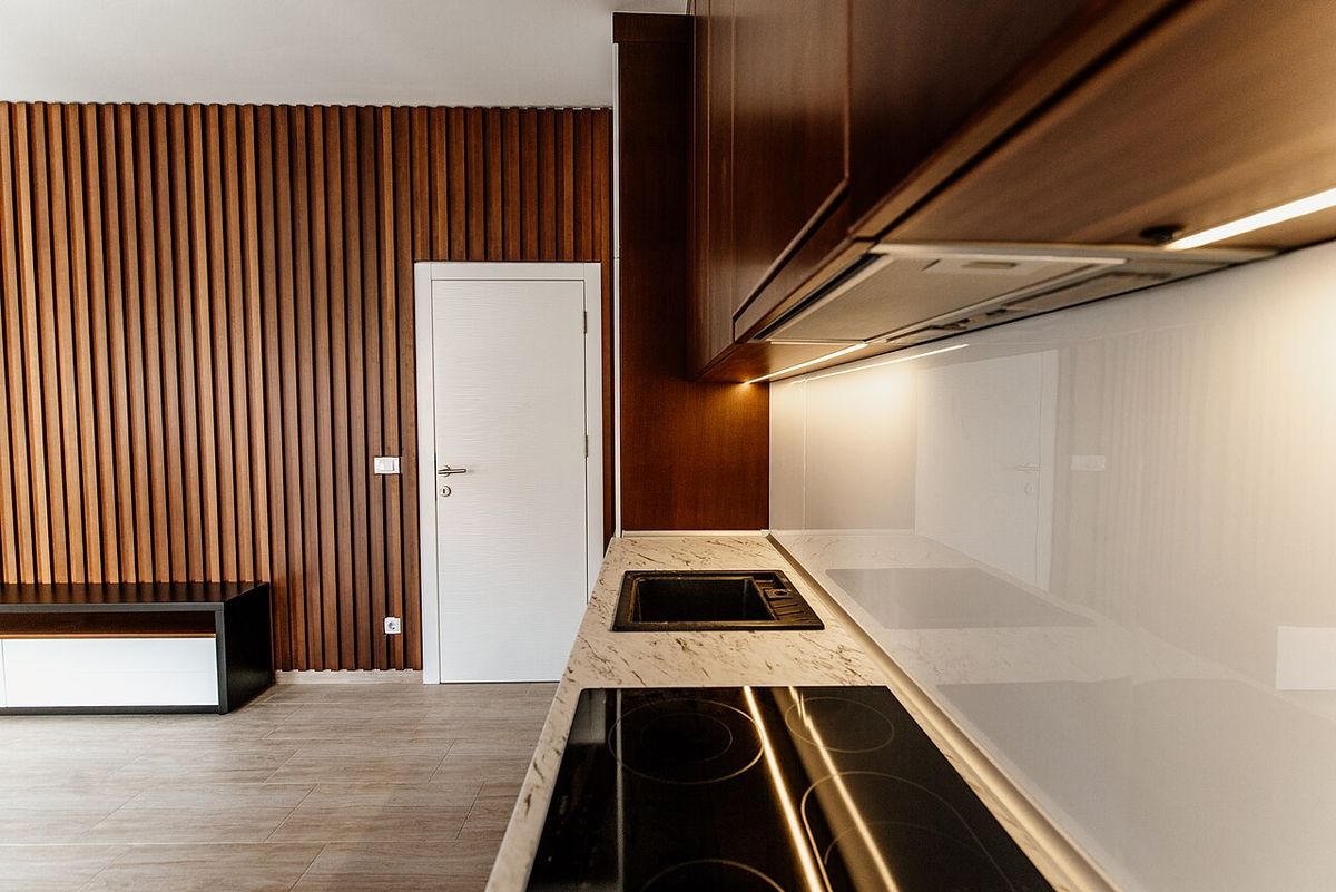 An open-plan living room and kitchen with a slatted wood wall