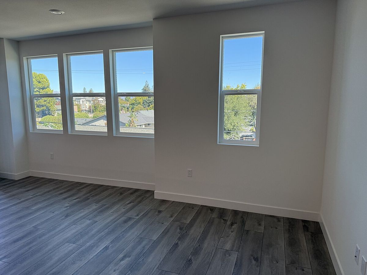 An empty room with large windows and a grey wood floor