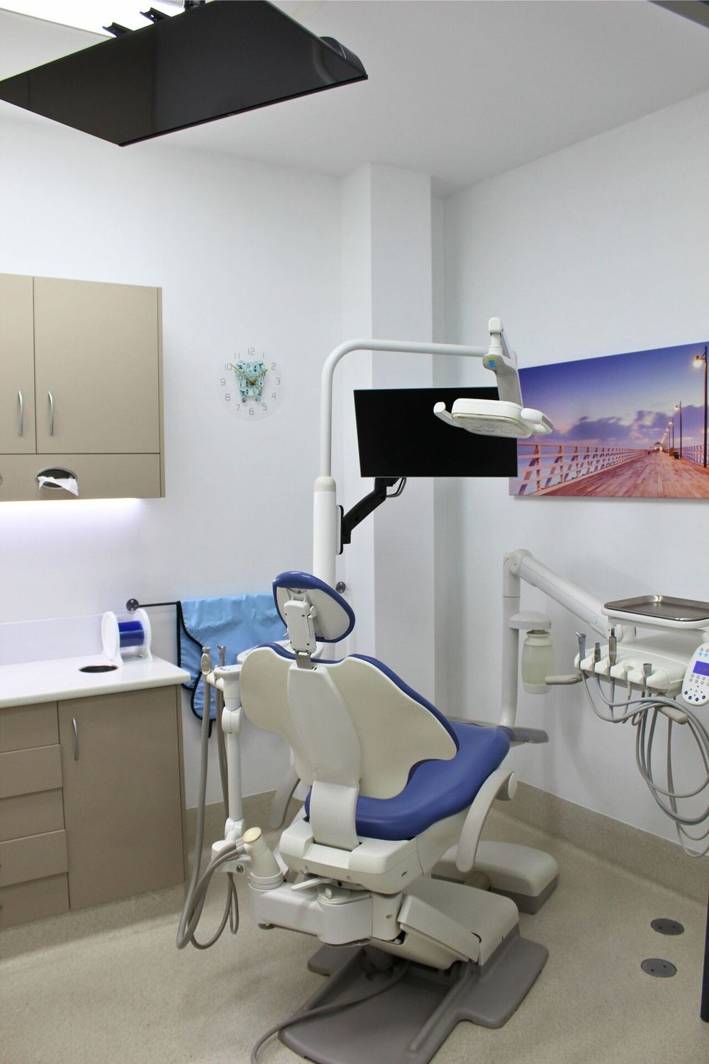 A modern white and blue dental chair under an examination light
