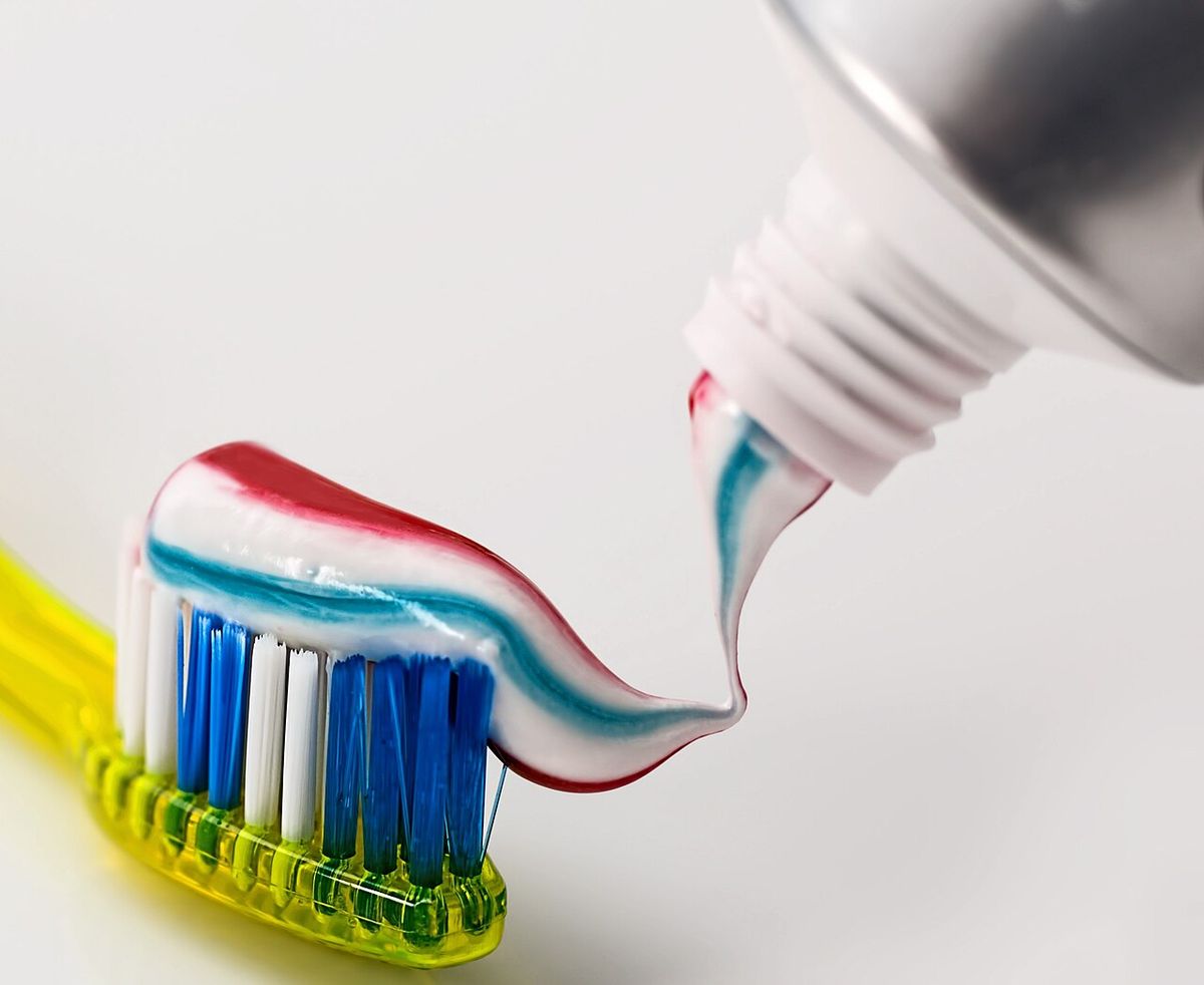 A yellow toothbrush with a swirl of striped toothpaste