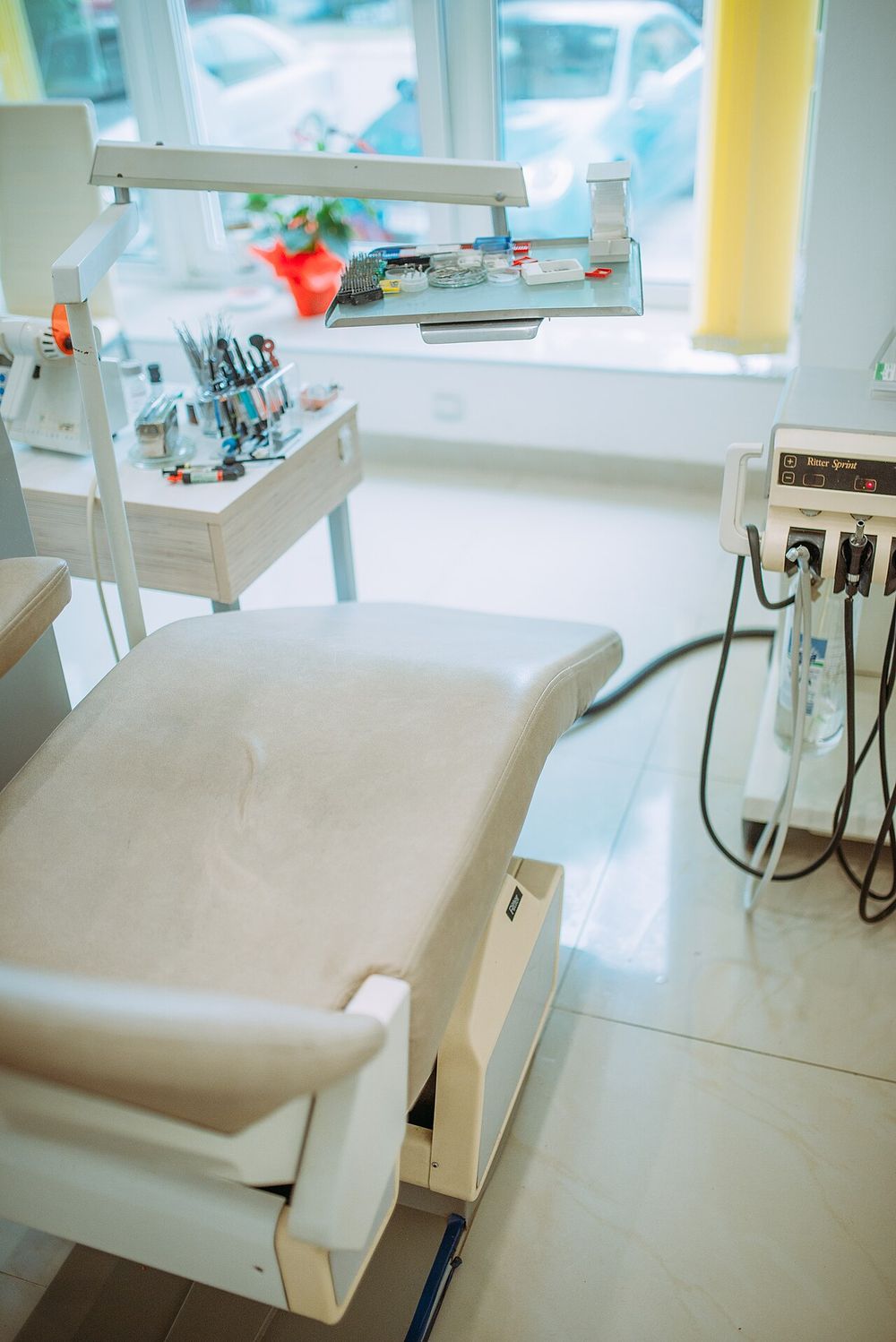 A bright treatment room with a dental chair and instruments by a window